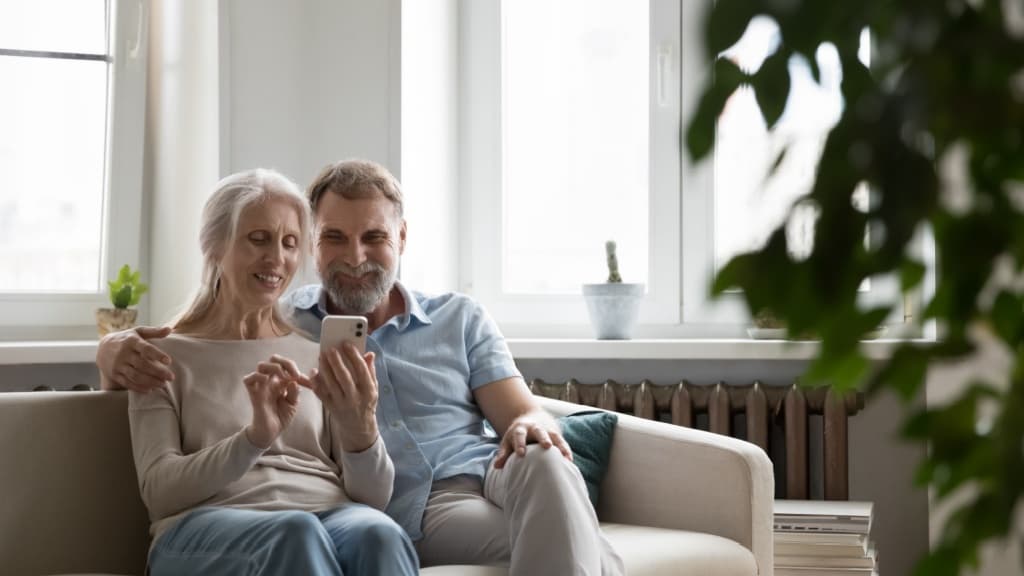 Smiling mature couple holding a cellphone.
